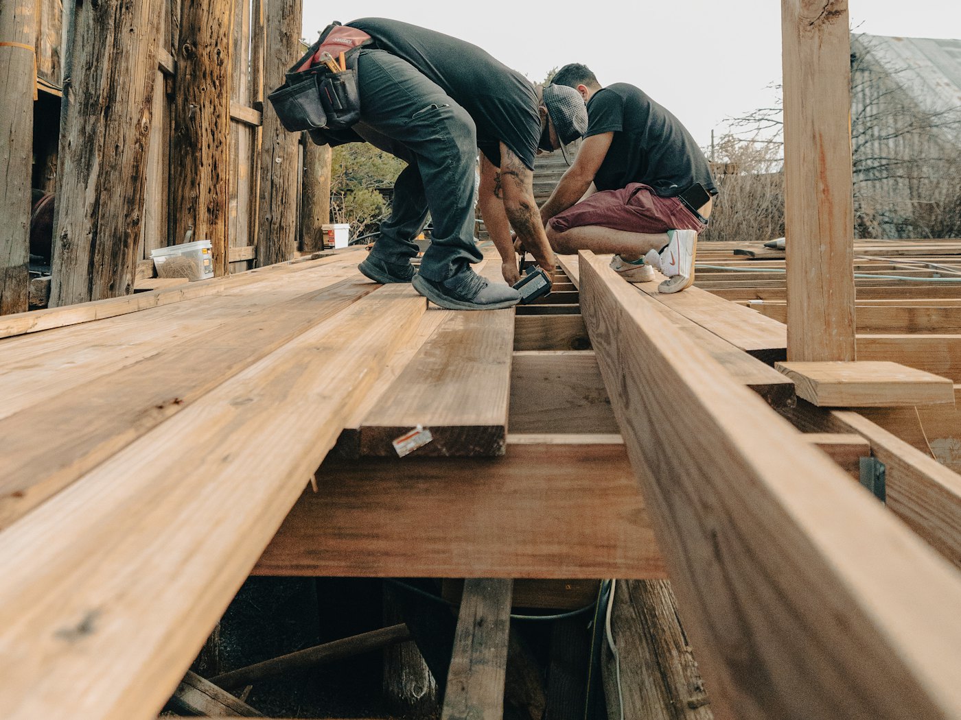 Two carpenters fastening deck boards over new joists