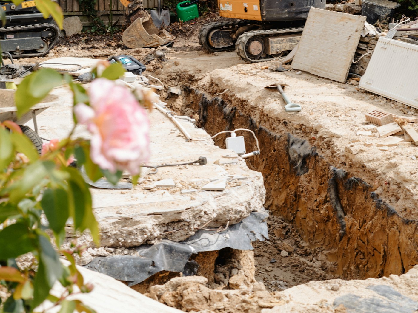 Mini excavator beside a freshly dug perimeter trench next to a house